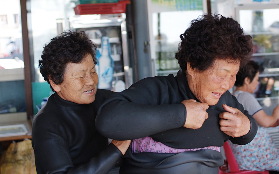 해녀복 입는 것을 서로 도와주는 이신자 해녀와 정양순 해녀