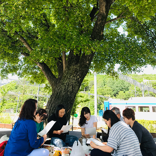 나무 그늘에서 함께 책을 나누다 