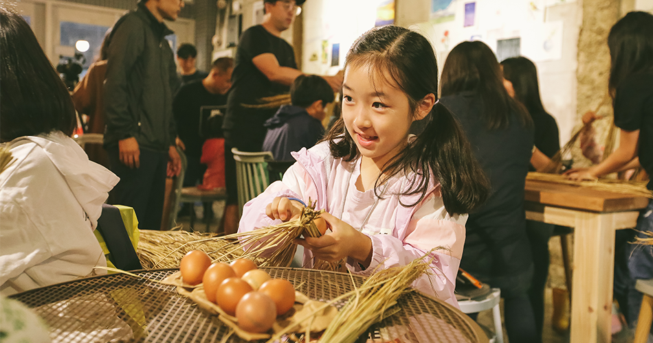 짚풀로 달걀꾸러미를 만드는 여자 아이